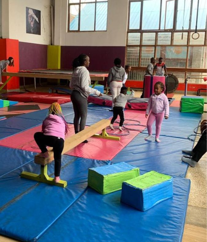 coach helping to teach students on a beam balancing skills